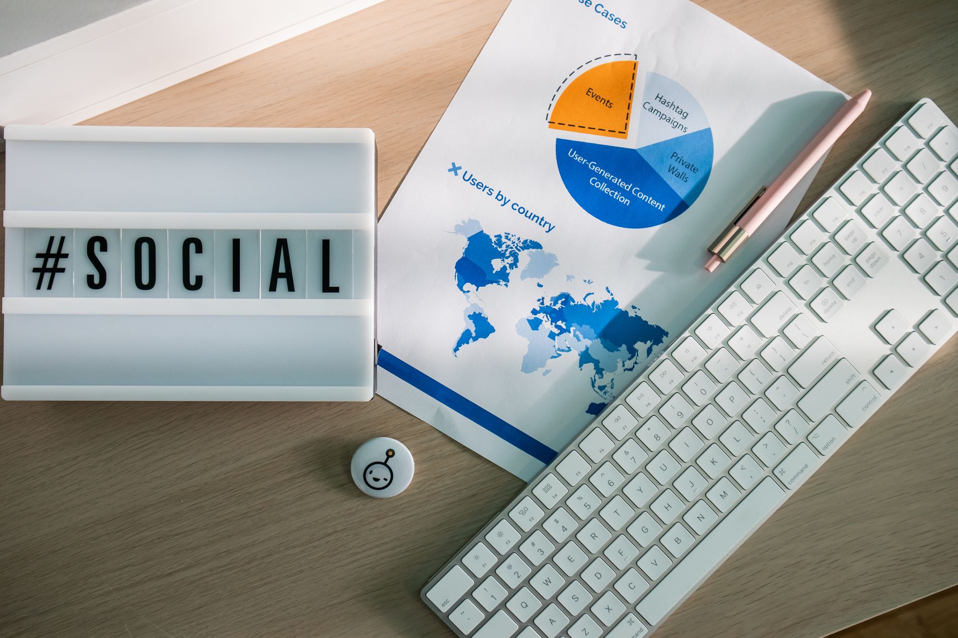 Schreibtisch von oben mit Tastatur, Hashtag-Symbol und Diagrammen zur Social-Media-Analyse