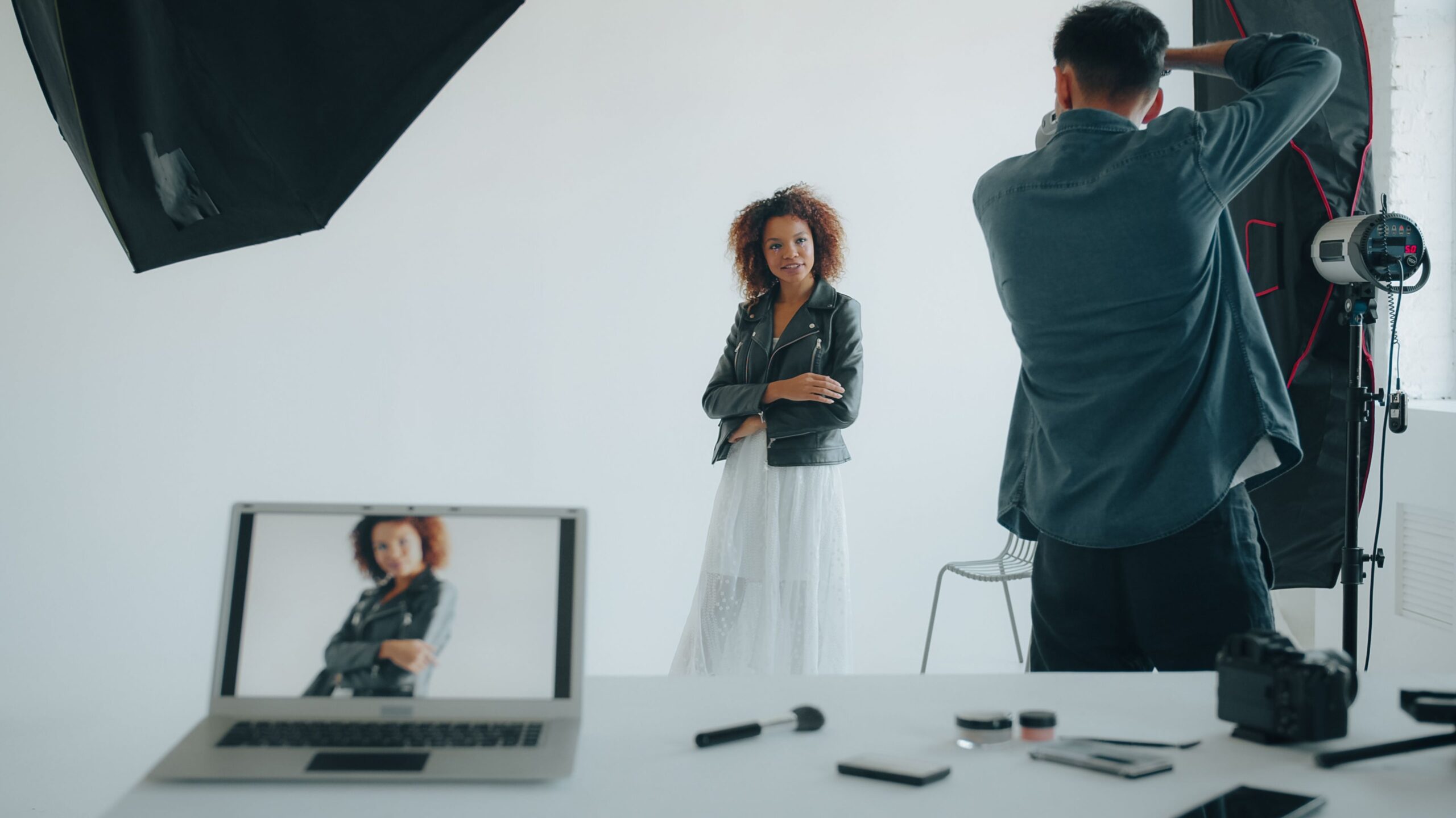 Fotograf fotografiert eine Frau in einem Studio mit professioneller Lichttechnik